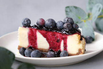 Sweet cheese pie poured jam and decorated fresh blueberries. Slice of tasty cheesecake on plate.