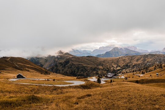 Picturesque scenery with rough steep rocky peak and hills covered with yellow grass under clouds in Dolomites mountain range in Italy