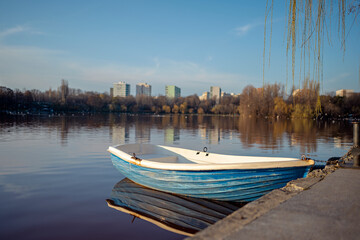 Small rowboat anchored by the shore on the lake resting in a very polluted red water