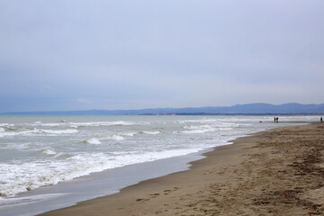 Winter beach with waves breaking on the shore and silhouettes of people in the background