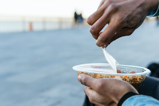 Crop anonymous ethnic male with appetizing healthy food with soft cheese cubes in plastic container to go