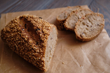 homemade bread sprinkled with flax seeds and sesame lies on a rustic plank table.