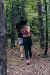 Young athletic couple is running outdoors in the wooded forest area