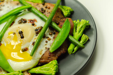 Fried portion of gammon served with egg, green beans, broccoli and sugar snap peas