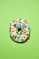 Tasty addicting dessert. Vertical shot of freshly baked round glazed donut with colorful sprinkles...