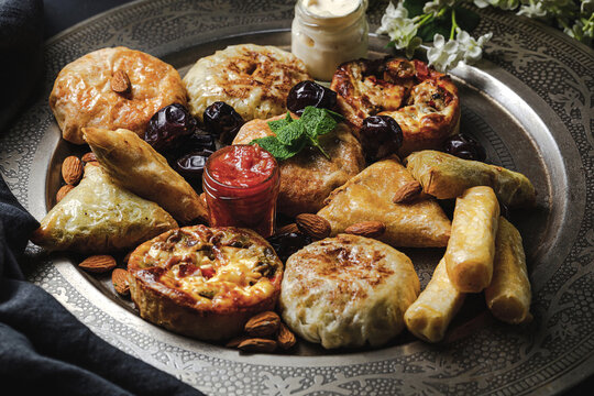 High angle of assorted tasty Arabic food with salsa and fresh mint leaves near almonds during Ramadan holidays