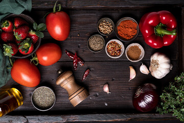 Top view of fresh ripe tomatoes and strawberry placed on wooden table with various spices and ingredients for Gazpacho soup recipe