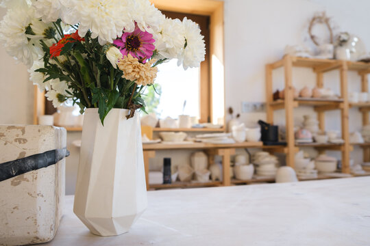 Handmade ceramic vase in pottery studio with blooming flowers