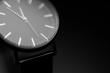 black modern analog wristwatch on a black background