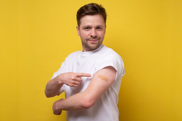 Caucasian man showing his vaccinated arm. He received a corona vaccine looking at camera.