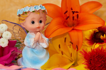 Fototapeta premium angel figurine with flowers,little angel decorated with flowers for the holiday
