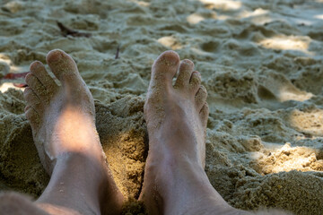 Fototapeta na wymiar feet on beach sand under tree shade