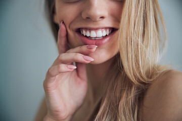 Female with a toothy smile touching her cheek with one hand