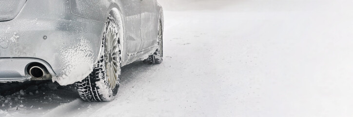 Silver car covered with ice parked on snow covered road, detail view to exhaust from behind,...