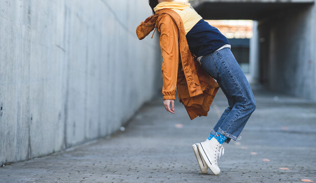Side view of cropped unrecognizable female teenager in casual clothes having fun on city road while looking forward