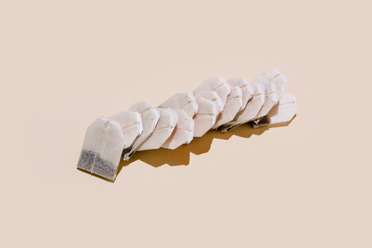 From above of paper tea bags arranged in row on beige background with empty space