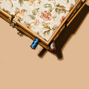 Top view of spools of cotton threads placed inside box with floral ornament on brown background