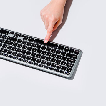 From above anonymous person pushing button on computer keyboard on gray background