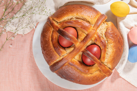 Portuguese traditional Easter cake. Folar with eggs on easter table. Blossom flowers and colorful painted eggs
