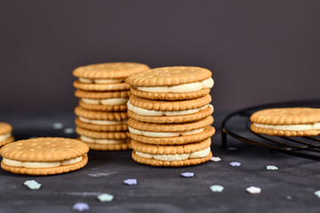 Stack of cream filled sandwich double cookies on dark background