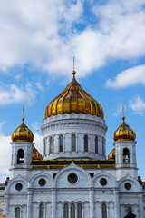 Fototapeta na wymiar The domes of the Cathedral of Christ the Savior, shot up close, against a blue sky with clouds on a sunny day. Architecture and travel concept.