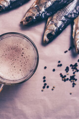 Obraz na płótnie Canvas Dried fish, beer mug on paper and brown background.