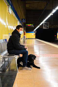 Male passenger in mask with guide dog on metro station