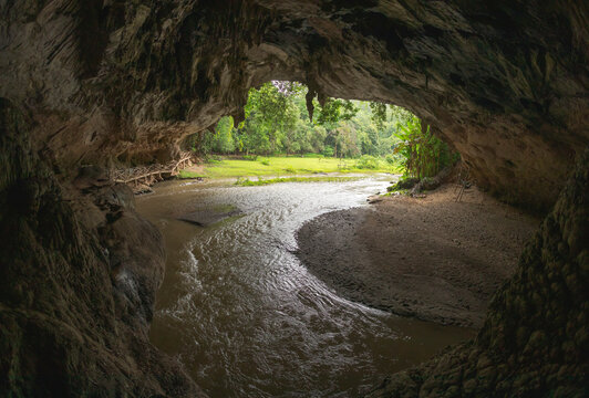Picturesque scenery of narrow river flowing through Tham Lot cave covered with lush green tropical vegetation in Thailand