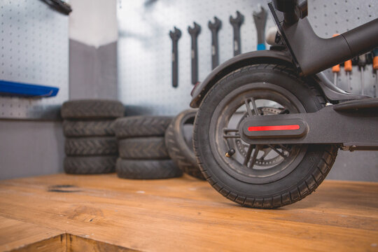 Incomplete electric scooter placed near wall with various repair tools and instruments in modern workshop