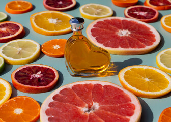 Fototapeta na wymiar Vitamin C serum in a heart shaped bottle on a slised citrus set. Orange, grapefruit, lime, tangerine, lemon. Organic SPA cosmetics with orange oil.