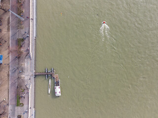 Top down aerial drone shot of a small ferry boat over the Rhein river in Basel city center, Switzerland during high water