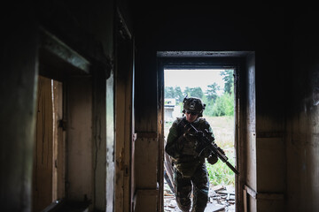 Soldier in full US MARSOC armed with assault rifle run through the abandoned building. Military clash.