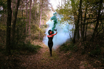 Sexy Teufelin steht im Wald. Sie hat die Hörner auf dem Kopf, eine schwarze Corsage. sie ist mit...