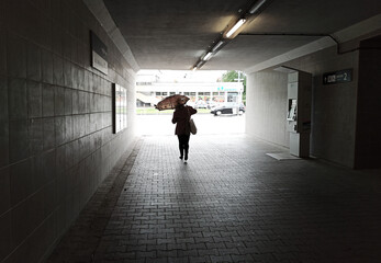 Cracow, Poland: A girl walking inside a tunnel subway of train station with umbrella in an urban city