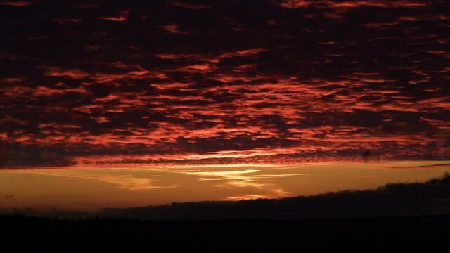 Dramatic red sunset reflecting on cloud blanket in nature, time lapse