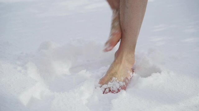 Caucasian man's feet fidget in freezing white snow, medium shot