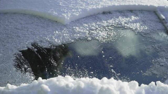 Windshield wipers on car working to move thick snow, slow motion shot