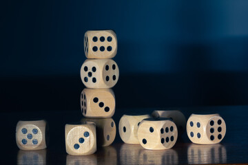 Wooden dice for board game stacked on wooden table and dark background.