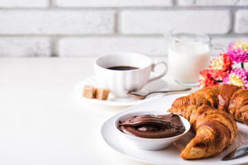 Croissant with chocolate hazelnut spread and cup of coffee