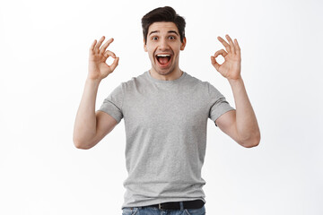 Excited man screams with joy and shows okay signs, rate super cool thing, praise excellent thing,...