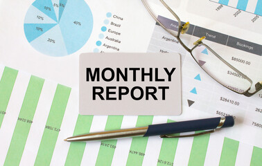 Monthly Report card with text Goals 2021 lies on financial charts with pen and eyeglass
