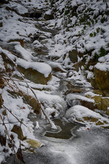 Ice-free little river in winter. Stream of river water. The snow cover. Winter abstract background.