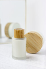 Glass matte cosmetic cream bottles with wooden top, eco cosmetics and mirror on white, lotion serum face body treatment