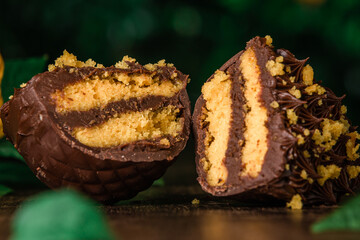 Stuffed chocolate easter egg with carrot cake filling on a wooden table with a nature background. Gourmet.