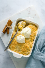 Apple and pear crumble with ice cream, streusel. Sweet dessert with stewed fruit topped crisp crumbly mixture served ice cream. Apple cobbler pie in large baking dish on table. Top view, vertical