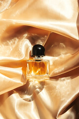 Glass perfume bottle on golden fabric, Top view