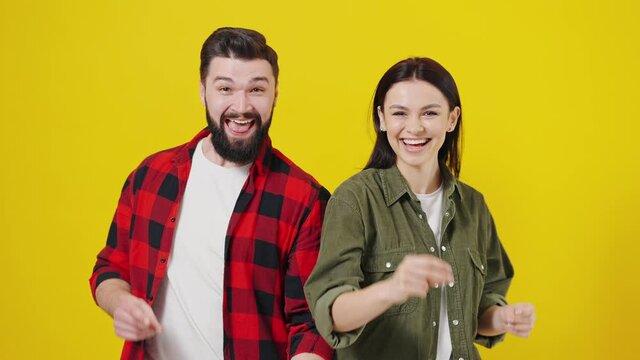 Beautiful young couple together standing over yellow background pointing with finger to the camera and to you, hand sign, positive and confident gesture from the front