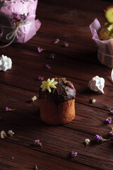 Easter cake on the festive table. Festive baked goods with exuberant spring colors on a dark woody background. Dried flowers in the decor of the composition.
