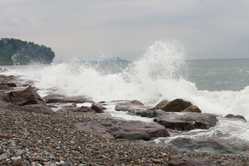 Waves crash against rocks on the shore of a pebble beach