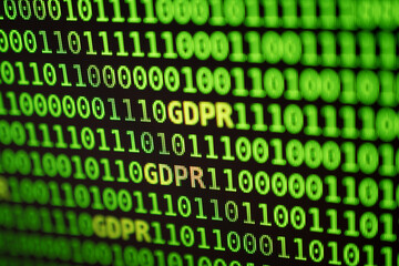 GDPR letters surrounded by green binary numbers on a real RGB display. Focused on GDPR letters, corners blurred by shallow depth of field. GDPR stands for General Data Protection Regulation.